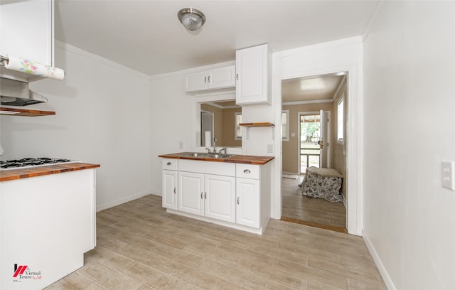 kitchen with light hardwood / wood-style floors, white cabinetry, butcher block counters, white gas stovetop, and sink