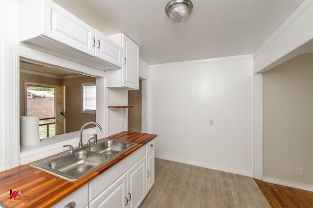 kitchen with white cabinets, light hardwood / wood-style floors, sink, and wood counters