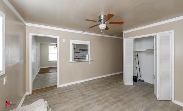 unfurnished bedroom featuring a closet, sink, light hardwood / wood-style flooring, crown molding, and ceiling fan