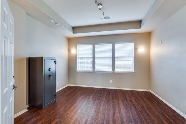 interior space featuring track lighting, a raised ceiling, and dark wood-type flooring