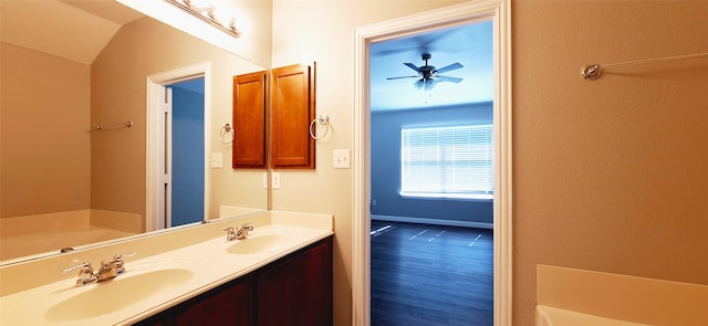 bathroom with ceiling fan, vanity, hardwood / wood-style flooring, a tub to relax in, and vaulted ceiling