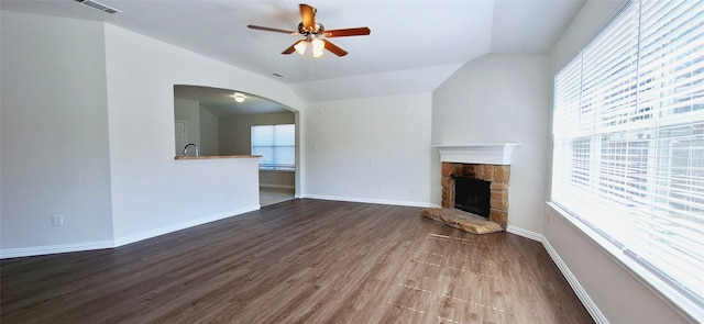 unfurnished living room featuring ceiling fan, lofted ceiling, sink, a stone fireplace, and hardwood / wood-style floors