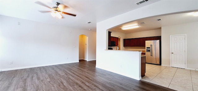 kitchen featuring stainless steel fridge, light hardwood / wood-style floors, ceiling fan, and kitchen peninsula