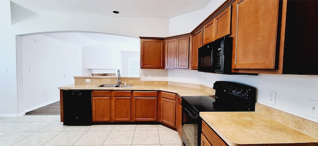 kitchen with black appliances, vaulted ceiling, sink, and light tile patterned floors