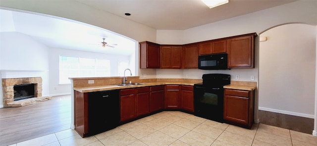 kitchen featuring ceiling fan, sink, light hardwood / wood-style flooring, black appliances, and a fireplace