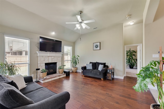 living room featuring a stone fireplace, vaulted ceiling, dark hardwood / wood-style floors, and ceiling fan