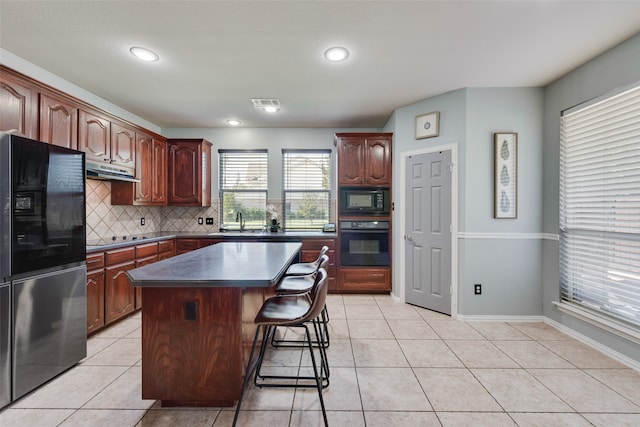 kitchen with light tile patterned flooring, sink, black appliances, a center island, and decorative backsplash