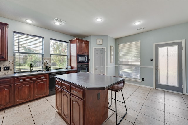 kitchen with backsplash, light tile patterned floors, black appliances, a center island, and sink