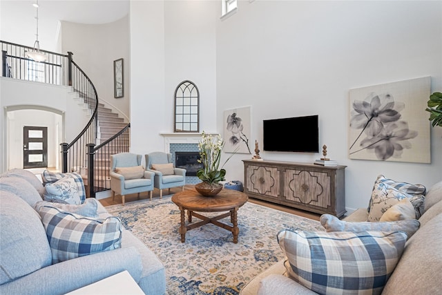 living room with a brick fireplace, a towering ceiling, and hardwood / wood-style floors