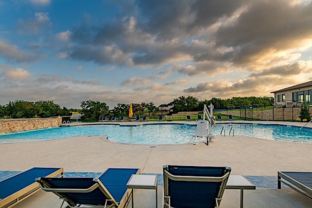 pool at dusk featuring a patio