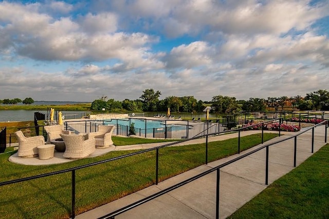 view of pool with a lawn and a water view