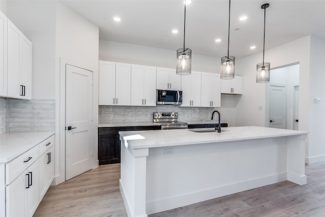 kitchen with a center island with sink, white cabinets, sink, and stainless steel appliances