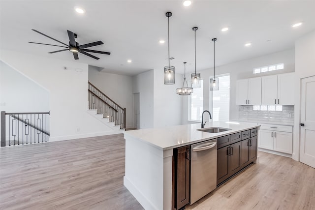 kitchen with pendant lighting, a kitchen island with sink, stainless steel dishwasher, ceiling fan, and white cabinetry