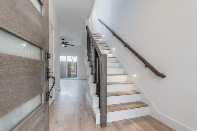 staircase with ceiling fan, hardwood / wood-style floors, and a towering ceiling