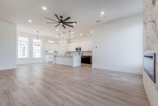 unfurnished living room featuring light wood-type flooring, heating unit, and ceiling fan