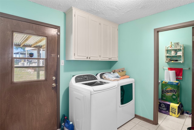 laundry room featuring a textured ceiling, washer and clothes dryer, light tile patterned floors, and cabinets