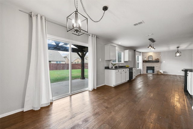 kitchen with white cabinets, sink, a stone fireplace, and hanging light fixtures