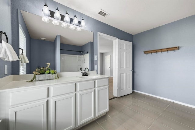 bathroom featuring tile patterned flooring, vanity, and a shower