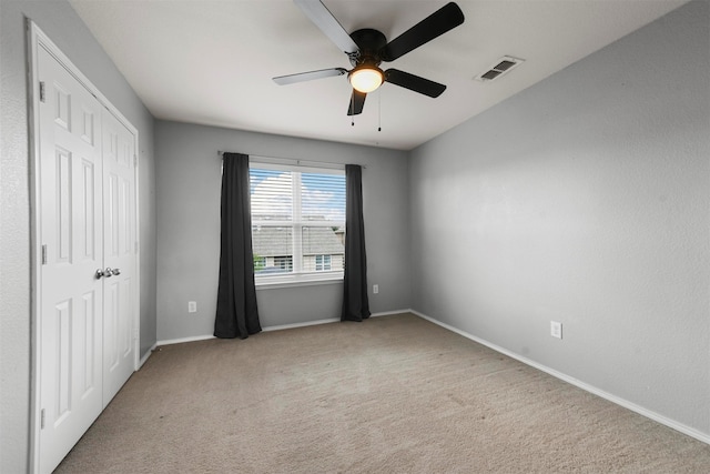 unfurnished bedroom with a closet, light colored carpet, and ceiling fan