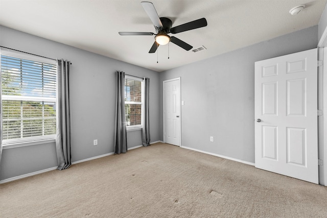 unfurnished bedroom featuring light colored carpet and ceiling fan