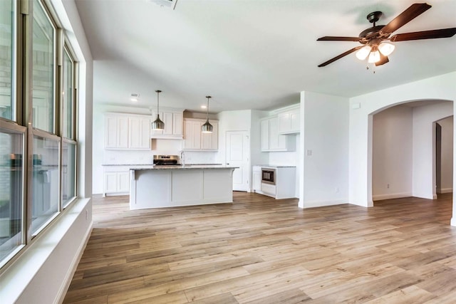 unfurnished living room featuring light wood-type flooring, lofted ceiling, sink, and ceiling fan