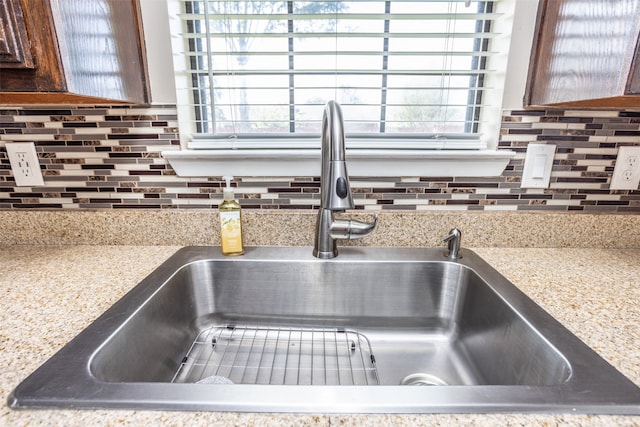 room details with dark brown cabinets, tasteful backsplash, and sink