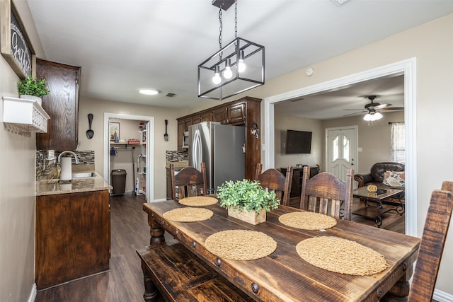 dining area featuring ceiling fan with notable chandelier, dark hardwood / wood-style floors, and sink