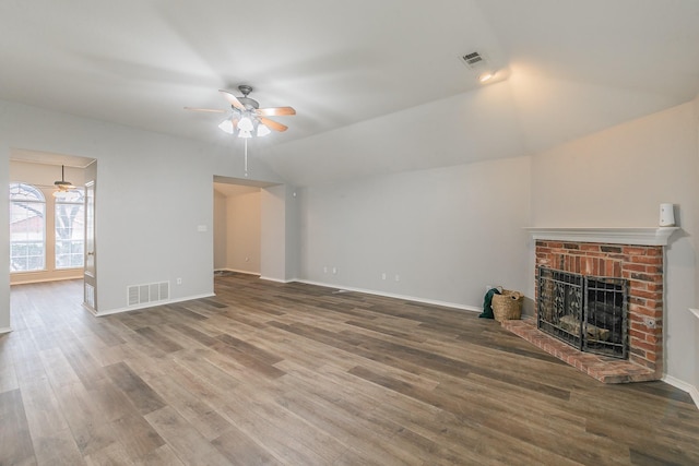 unfurnished living room featuring a brick fireplace, visible vents, vaulted ceiling, and wood finished floors