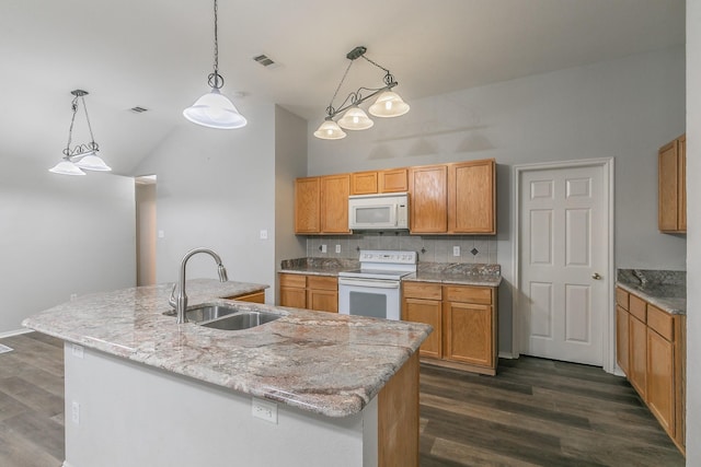 kitchen featuring pendant lighting, white appliances, a sink, and an island with sink