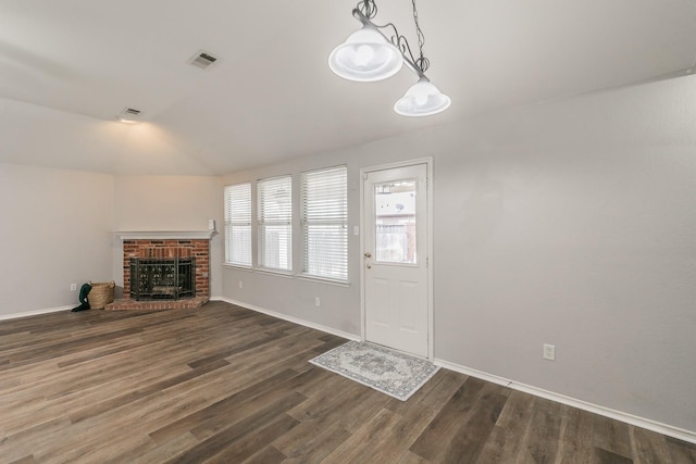 unfurnished living room with visible vents, baseboards, dark wood-type flooring, vaulted ceiling, and a fireplace