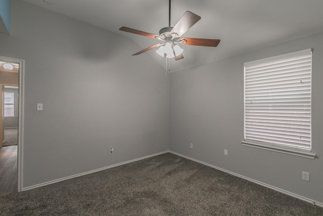 empty room with lofted ceiling, dark colored carpet, ceiling fan, and baseboards