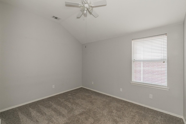 spare room featuring visible vents, dark carpet, a ceiling fan, vaulted ceiling, and baseboards