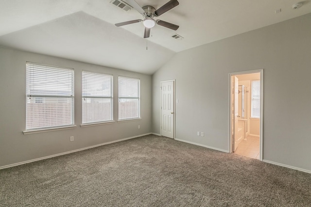 empty room featuring light carpet, visible vents, vaulted ceiling, and a ceiling fan