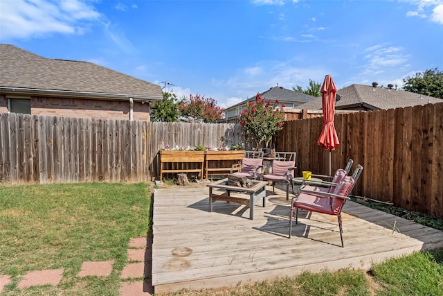 deck featuring a fire pit, a yard, and a fenced backyard