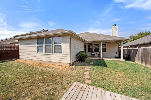 rear view of property featuring a yard, a fenced backyard, a patio, and a chimney