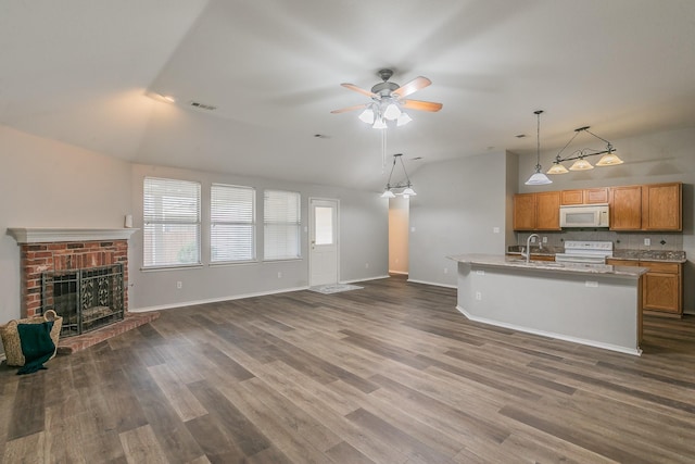 kitchen featuring white appliances, a center island with sink, open floor plan, vaulted ceiling, and light countertops