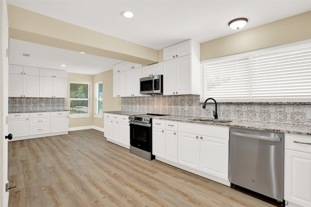 kitchen with backsplash, white cabinetry, and stainless steel appliances