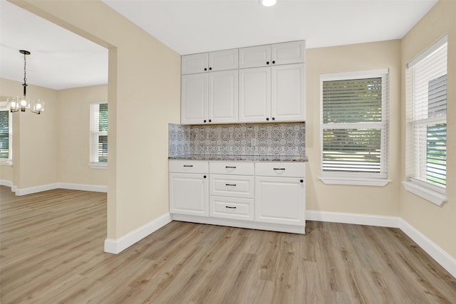 kitchen featuring a healthy amount of sunlight, white cabinetry, decorative backsplash, and pendant lighting