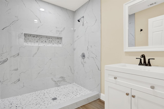 bathroom with a tile shower, hardwood / wood-style flooring, and vanity