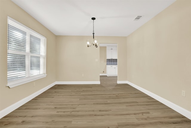 unfurnished dining area with an inviting chandelier and light hardwood / wood-style flooring