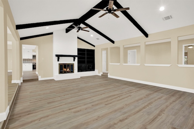 unfurnished living room with light hardwood / wood-style floors, lofted ceiling with beams, a fireplace, and ceiling fan