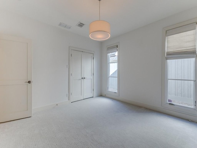 spare room with carpet flooring, visible vents, and baseboards