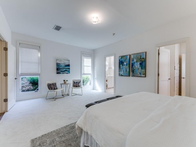 carpeted bedroom with visible vents and ensuite bathroom