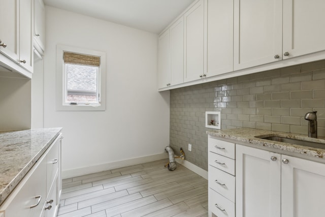 laundry room with washer hookup, cabinets, light hardwood / wood-style floors, and sink