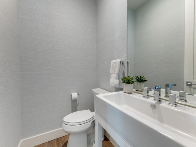 half bathroom featuring a sink, tile walls, and toilet