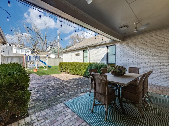 view of patio / terrace featuring outdoor dining area, a playground, fence, and a ceiling fan