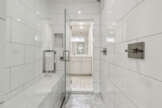 bathroom featuring a tile shower, tile walls, tile patterned flooring, and vanity