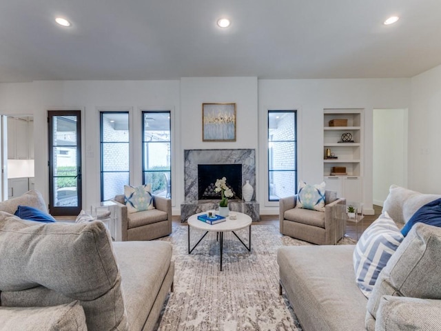 living area featuring built in shelves, a high end fireplace, wood finished floors, and recessed lighting