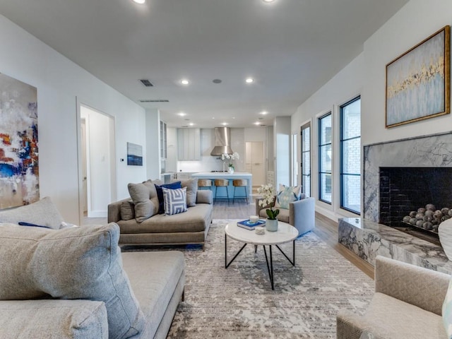 living area featuring a fireplace, light wood finished floors, recessed lighting, visible vents, and baseboards