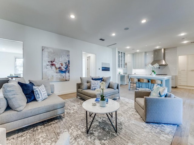 living room with visible vents, baseboards, light wood-style flooring, and recessed lighting